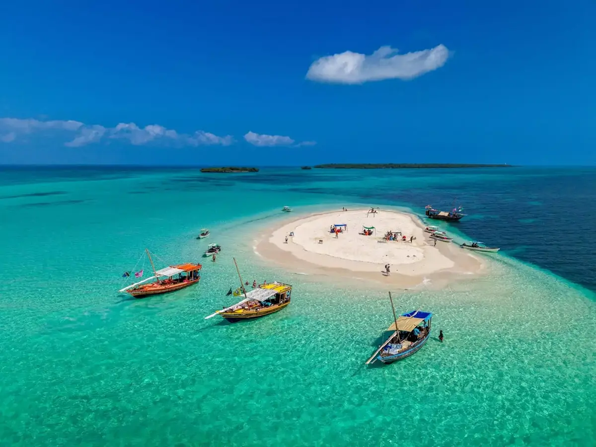 Traditional wooden dhow boats anchored beside a white sandbank in turquoise water, Zanzibar